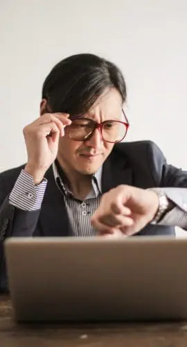 Confused businessman checking time on wristwatch