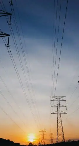 Modern power lines against bright setting sun