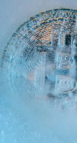 Prague, Czech Republic - October, 2019: Silver Bitcoin, bit coin online digital currency frozen in the blue ice. Concept of block chain, crypto market crash. Frozen crypto money, depreciation