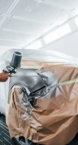 Professional painting a car in a paint booth