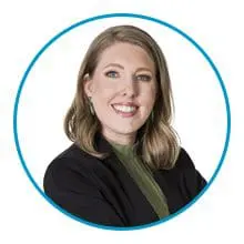 A smiling person with shoulder-length hair, wearing a black jacket and green top, is framed within a blue circle.