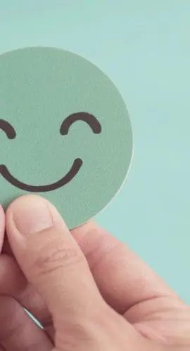 Hands holding sad face hiding behind happy face, bipolar and depression, mental health, split personality,  mood change,