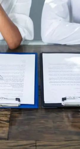 Two Businesspeople Working On Contract Paper In Office