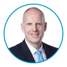 A bald man in a suit and tie is shown inside a blue circular border.