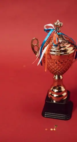 A trophy with tied ribbons on red background
