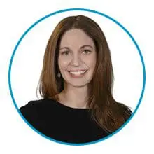 A person with long brown hair is smiling and wearing a black top inside a blue circular border.