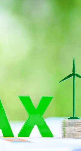Clean, renewable energy or electricity production tax credits and incentives, financial concept : Green energy symbols atop coin stack e.g solar panel, wind turbine, fuel cell battery and the word TAX