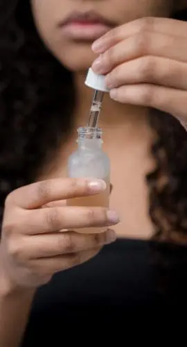 Person holding clear glass bottle