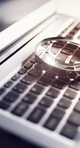 Magnifying glass on laptop keyboard searc for online documents background