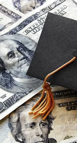 Miniature graduation cap on hundred dollar bills