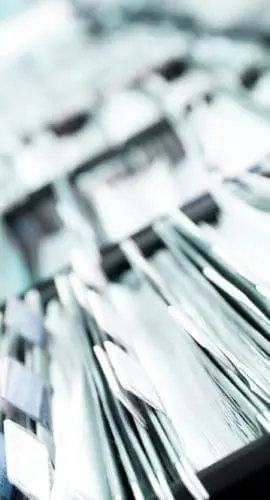 Multiple rows of filing cabinets in an office or medical establishment, overflowing with files.  Narrow depth of field to emphasize the "neverending" feeling