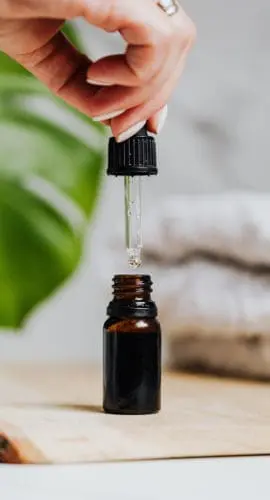 Person holding a dropper of brown bottle