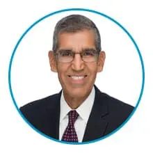 A person wearing glasses, a suit, and a tie is smiling inside a blue circle.