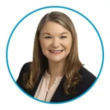 A person with long wavy hair wearing a blazer and smiling, framed within a blue circle.