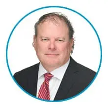 A person in a suit and red striped tie is shown within a blue circular border.