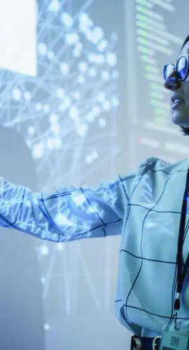 Young Female Teacher Giving a Data Science Presentation in a Dark Auditorium with Projecting Slideshow with Artificial Intelligence Neural Network Architecture. Business Startup and Education Concept