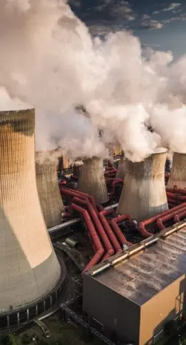 Aerial view of building exterior of a coal fired power station. Large cooling towers emitting steam into to air. Great for global warming, climate change and pollution themes.