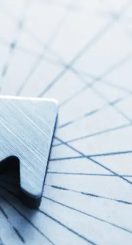 An arrow, photographed with a very shallow depth of field, sits on top of an old map lined with compass lines and navigational aids.