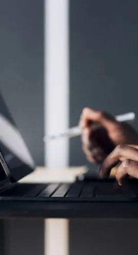 Unrecognizable African-American business woman typing notes on a keyboard while having online web conference on a digital tablet in a restaurant