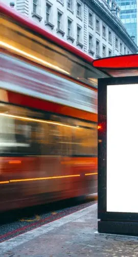 A blank billboard at a bus station at night