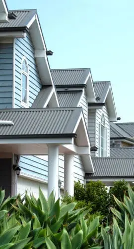 Frontal view of double-story townhouses characterized by their distinctive weatherboard wall cladding and corrugated metal roofs