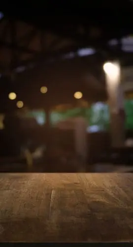 Empty dark wooden table in front of abstract blurred bokeh background of restaurant . can be used for display or montage your products.Mock up for space