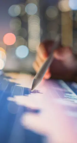 A close-up of a person using a digital tablet with a stylus to analyze financial data, representing consumer financial services. The glowing screen displays graphs and charts, symbolizing data-driven insights, regulatory compliance, and consumer protection in the evolving landscape of consumer finance.