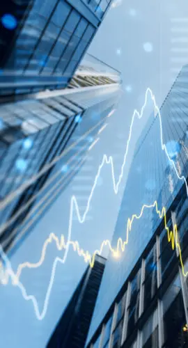 A double exposure image of skyscrapers with overlay of financial graphs, set against a blurred background, illustrating the concept of business growth