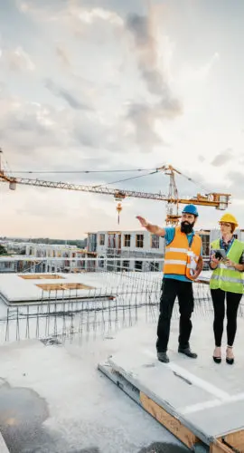 Employees working on construction site, wearing protective equipment and discussing next construction phase - full length models visible on the image