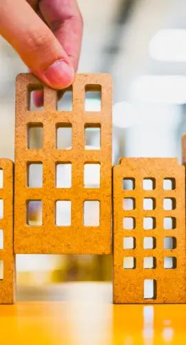 Hand choosing mini wood house model from model on wood table, selective focus, Planning to buy property. Choose what's the best. A symbol for construction ,ecology, loan concepts