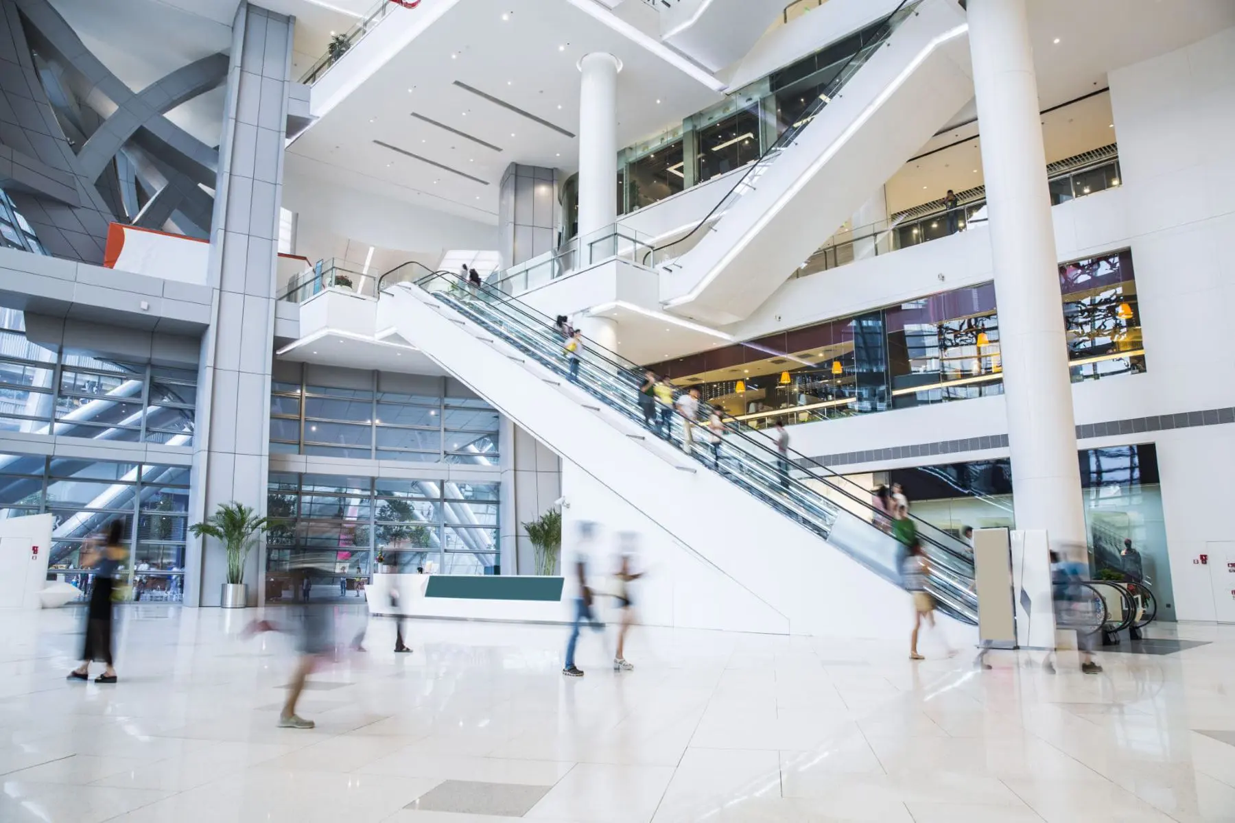 Modern shopping mall interior with escalators and retail storefronts, representing commercial real estate and retail center financing.