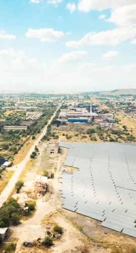 Aerial fly over view of solar power plant or farm next to abandoned industrial complex in Rustavi Georgia illustrating contrast of renewable energy progress and decaying polluting heritage