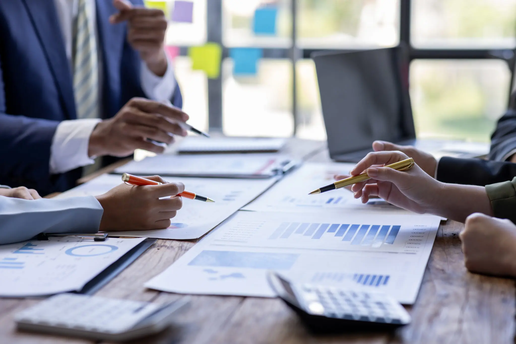 Group of business professionals reviewing market data, charts, and balance sheets during a strategy meeting on commercial real estate finance.