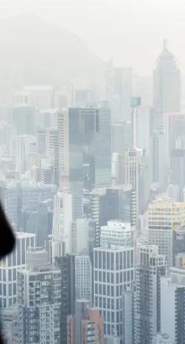 Businesswoman talking on phone from office window overlooking Hong Kong cityscape