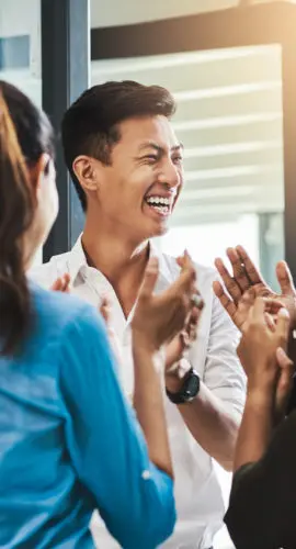 Shot of a group of young businesspeople standing together and clapping in a modern office