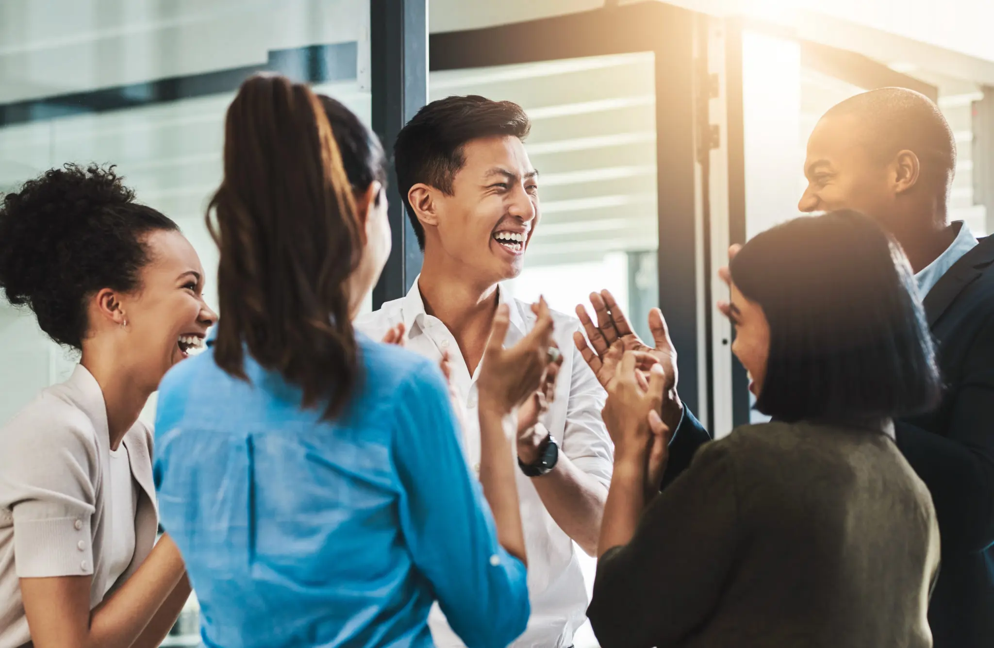 Shot of a group of young businesspeople standing together and clapping in a modern office