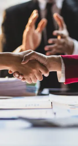 Handshake between business professionals finalizing a commercial real estate lending agreement involving carveouts, mortgage terms, and recourse liability.