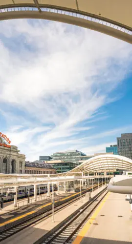 A view from above the train platfroms of Denver's Union Station, looking out to the modern office buildings of the city's downtown district.