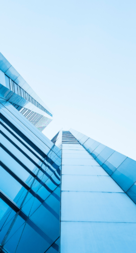 Upward view of a modern glass skyscraper reflecting blue sky, representing FBT Gibbons Law Firm's leading litigation, corporate, and regulatory compliance services for manufacturing, energy, financial services, and life sciences clients.
