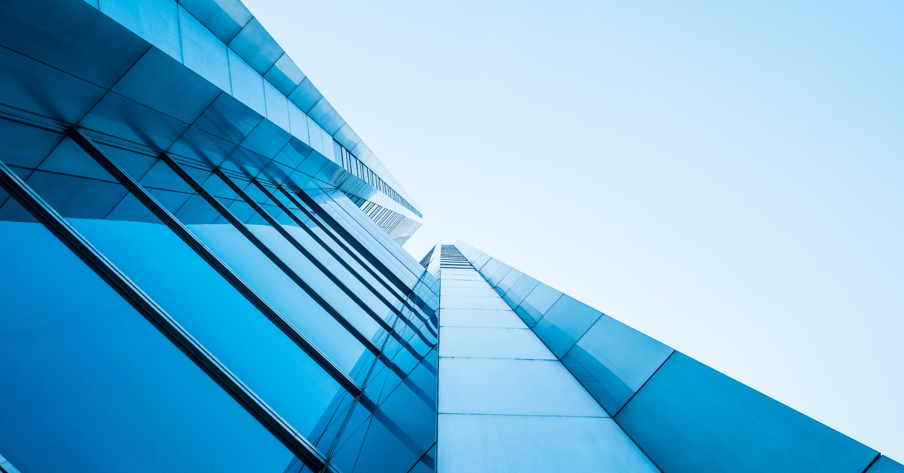 Upward view of a modern glass skyscraper reflecting blue sky, representing FBT Gibbons Law Firm's leading litigation, corporate, and regulatory compliance services for manufacturing, energy, financial services, and life sciences clients.