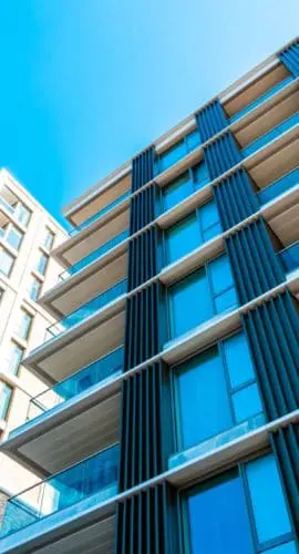 Modern multifamily apartment buildings photographed from ground level against a clear blue sky, representing affordable housing and real estate development