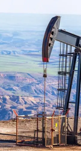 Oil pump jack operating above an arid canyon landscape, illustrating produced water management challenges in the Southwest.