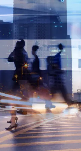 Motion-blurred professionals crossing a city street at dusk, symbolizing the pace of risk in today's insurance industry.