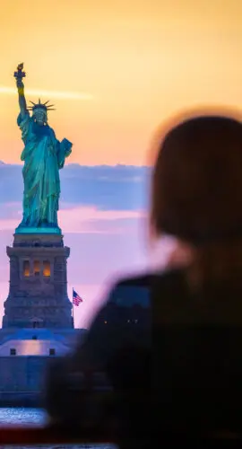 A young woman watches the Statue of Liberty, from the Staten Island Ferry