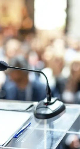 Microphones in focus at business conference, corporate presentation, workshop, coaching training, news conference, company meeting, public or political event. Public speaking concept.