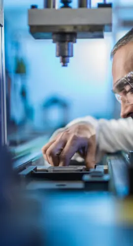 Mid adult male engineer examining machine part on a production line in a factory.