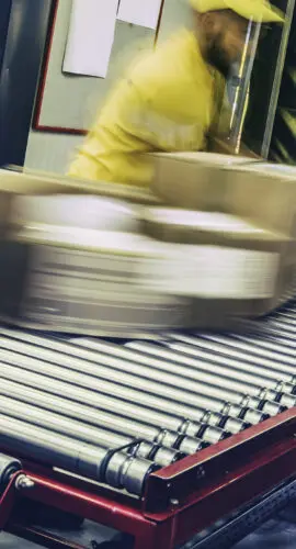 Group of distribution warehouse workers sorting packages that are moving on a conveyor belt. Blurred motion.