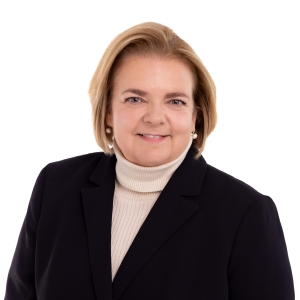 A professional portrait of a woman wearing a black blazer over a yellow top.