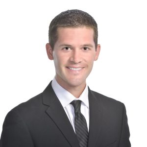 A smiling individual in professional attire against a white background.