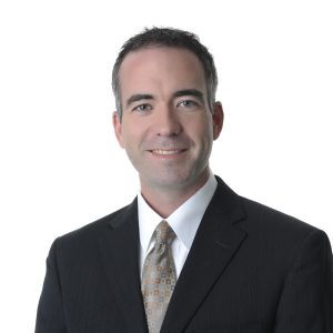 A smiling individual in professional attire with a white background.